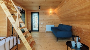 A wooden cabin interior with a loft bed, a sofa, a table with cups, and a ladder. - Chalet Kvirike (Kobuleti)