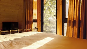 A wooden room with a bed, large windows, and a TV. - Chalet Kvirike (Kobuleti)