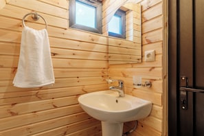 A wooden cabin bathroom with a white sink, a towel hanging on a metal ring, and a small window above the sink. - Chalet Kvirike (Kobuleti)