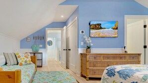 A bedroom with two beds, a dresser, a TV, and a view of the outdoors.