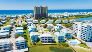 A coastal resort area with multiple buildings, including a prominent hotel with a red roof, surrounded by smaller structures and a beach. - Lagoon Front | Pet Friendly | Deeded Beach Access, Pool & Pier (Gulf Shores)