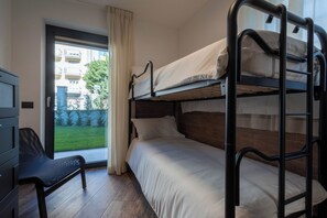 Habitación con literas y vista a un área verde y edificios.