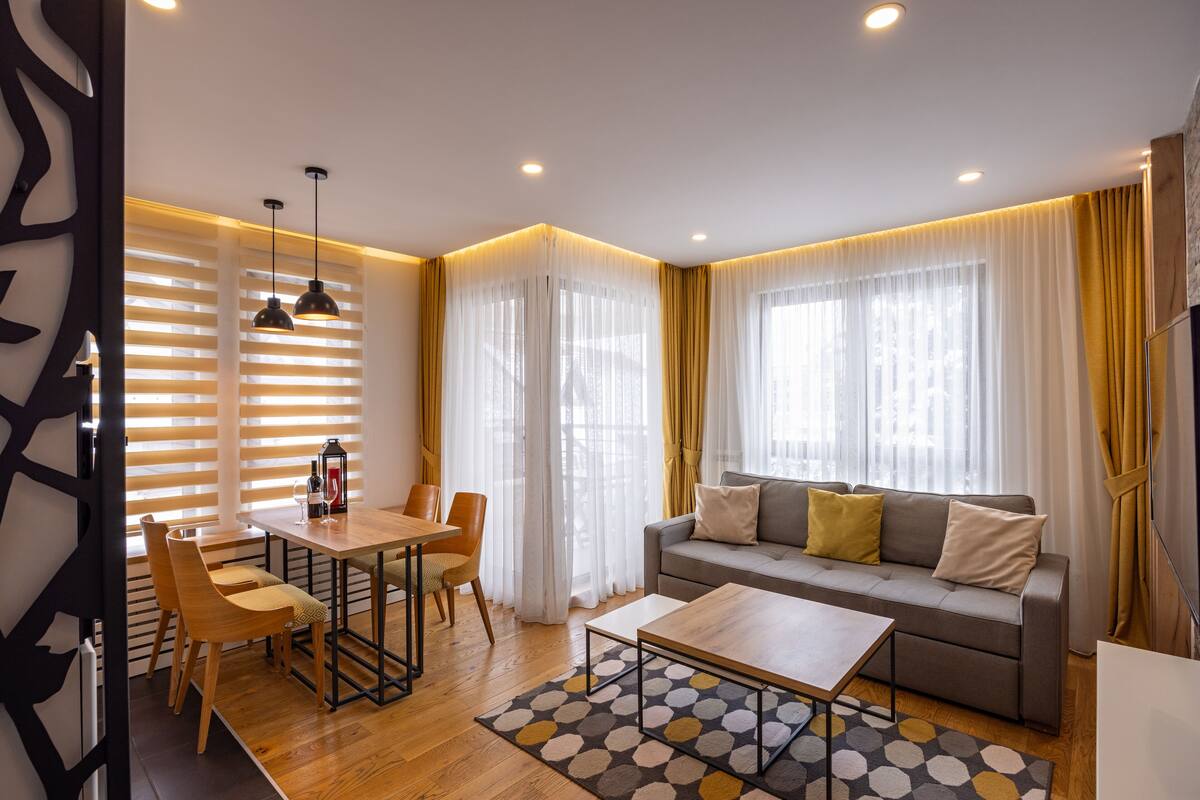 Ein stilvolles Wohnzimmer mit Sofa, Couchtisch, Esstisch und Stühlen.