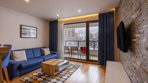 A modern living room with a blue sofa, wooden coffee table, and a patterned rug. - Apartments by Bor (Zlatibor)