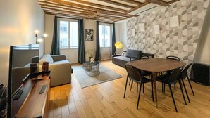 A modern living room with a wooden ceiling, a dining area with a round table, and a sofa.