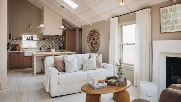 Una sala de estar moderna con un sofá blanco, una mesa de centro de madera y una chimenea.