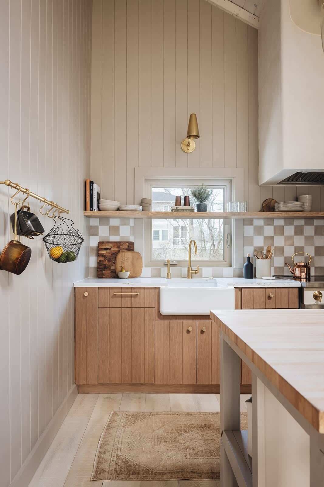 A kitchen with wooden cabinets, a white countertop, a sink, and a window with a view.