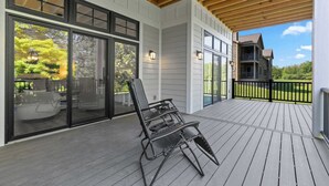 Una terrazza coperta con una sedia, ampie porte scorrevoli in vetro e vista su una casa.