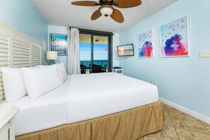 Une chambre d’hôtel avec un lit, un ventilateur de plafond, une télévision et un balcon avec vue.