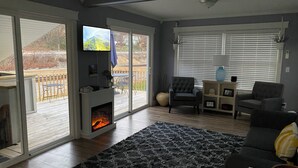 Een woonkamer met een open haard, een televisie en uitzicht op de omgeving.