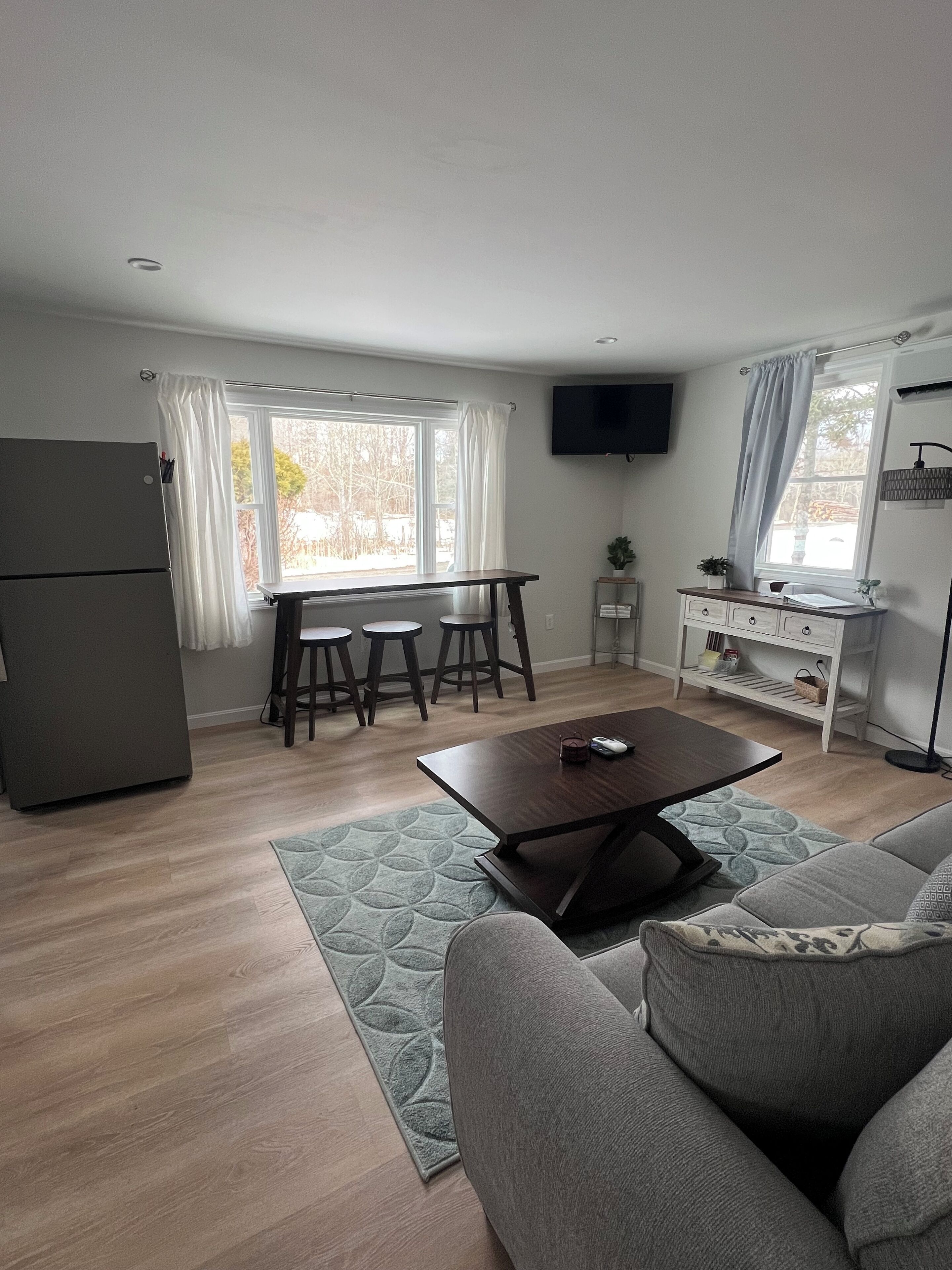 Een kleine woonruimte met een eethoek, een bank, een flatscreen-tv en een kitchenette.