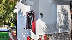 A building with a cylindrical structure, a small window with a red frame, and a stone base. - Olivegrove Holiday House (Massalubrense)