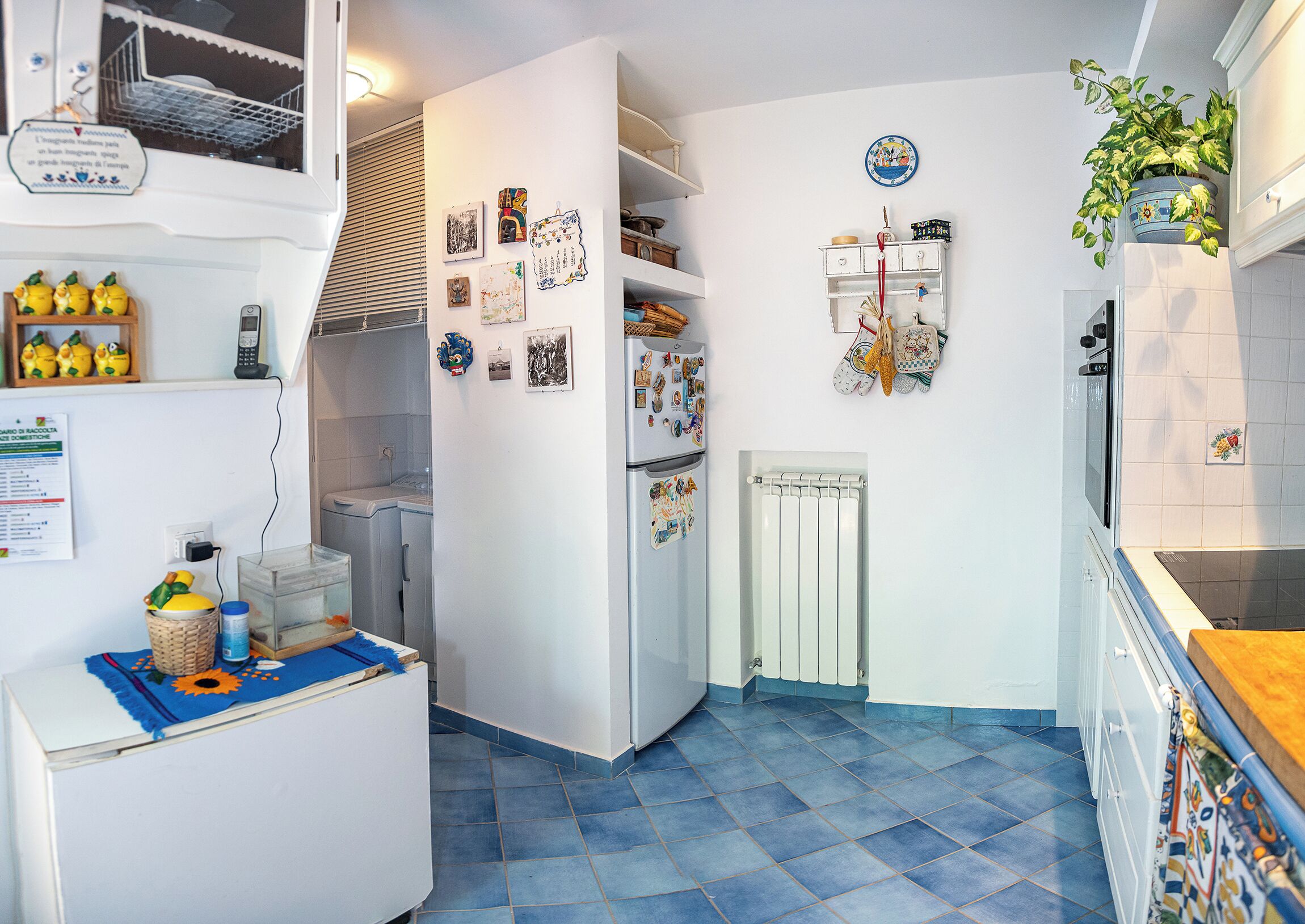 Een compacte keuken met een koelkast, een inbouwoven en een radiator.
