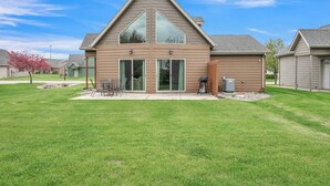 A modern two-story house with a large front porch, sliding glass doors, and a well-maintained lawn.