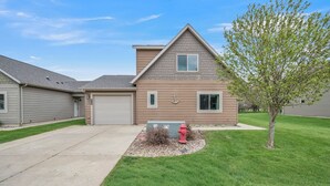 A residential house with a garage, a small front yard with a tree, and a red fire hydrant.