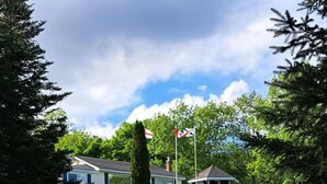 A grassy area with a building, a flagpole, and a gazebo. - Lochaber Lake View Cottage (Antigonish County)