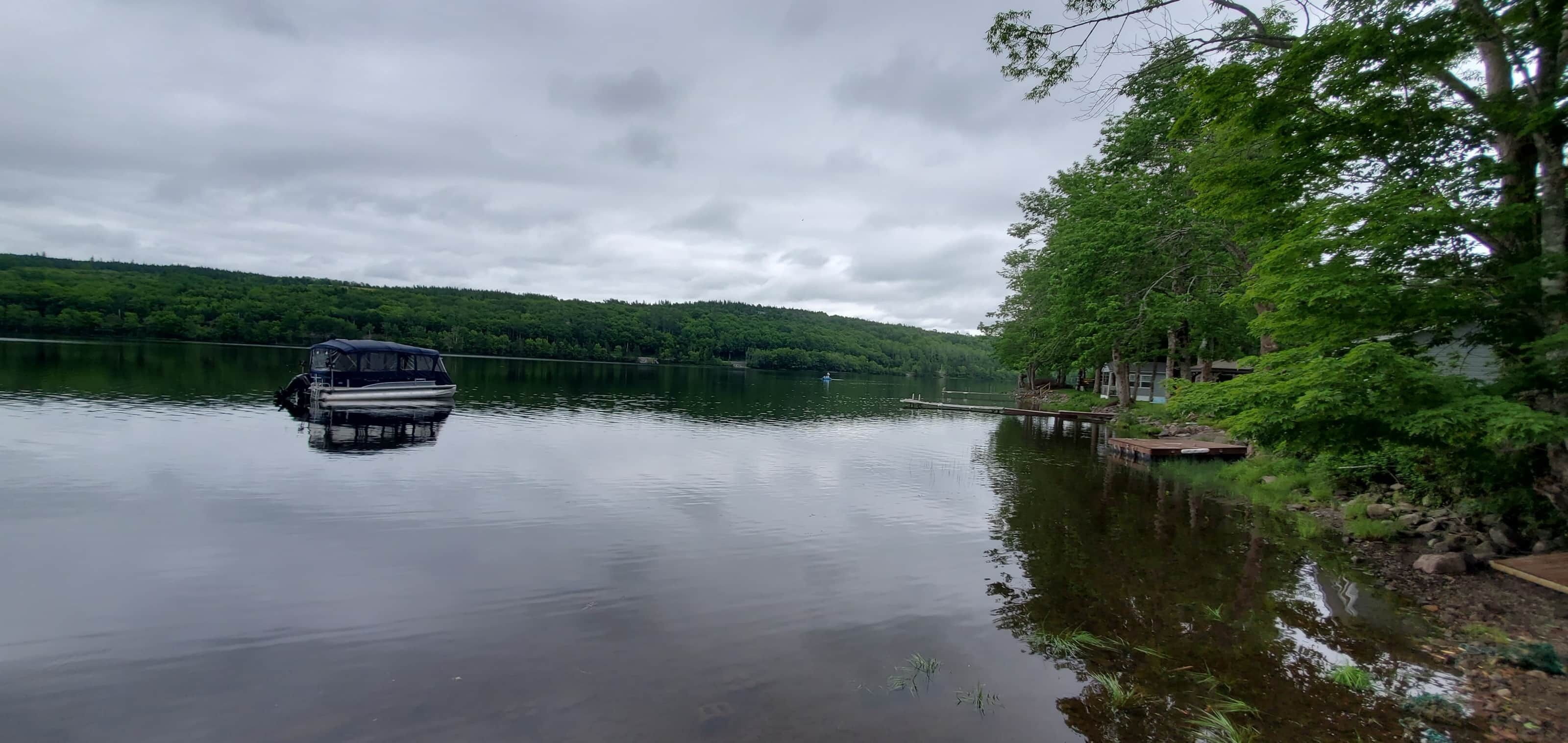 A calm lake with a dock and a boat.
