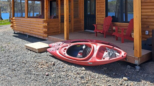 Une cabane en bois dotée d’un porche couvert, d’un jacuzzi et offrant une vue sur un lac.