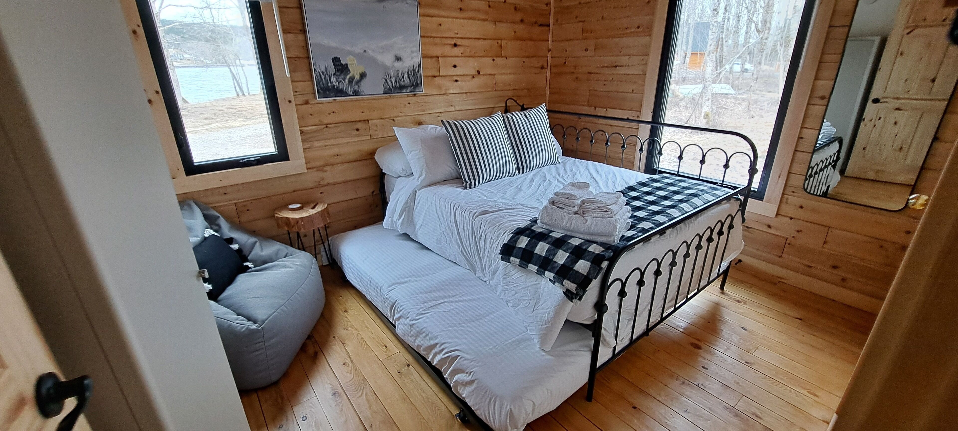 A cozy wooden cabin room with a bed, a small round table, and a bean bag chair.