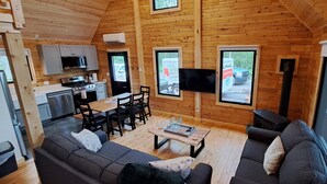 Un intérieur de chalet chaleureux comprenant un coin repas, une cuisine et un espace salon.