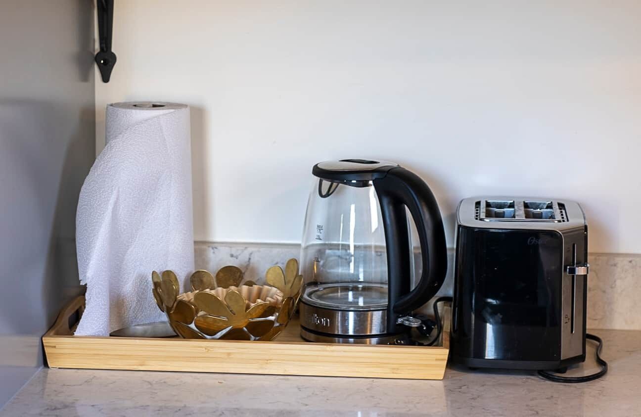 Una encimera de cocina con una cafetera, un tostador y un rollo de toallas de papel.