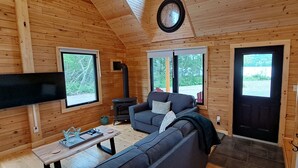 Un intérieur de chalet chaleureux avec un canapé, un téléviseur, une cheminée et des murs en bois.