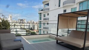 En takterrass med en pool, två solstolar och utsikt över stadsbilden.