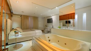 A modern bathroom with a large bathtub, a sofa, and a television. - Apple Motel - Adults Only (São Paulo)