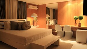 A modern hotel room with a large bed, a desk, two chairs, a bench, and a mirror. - Apple Motel - Adults Only (São Paulo)