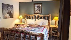 Un lit avec une tête de lit en bois rustique, une courtepointe à motifs animaliers et deux lampes de chevet.