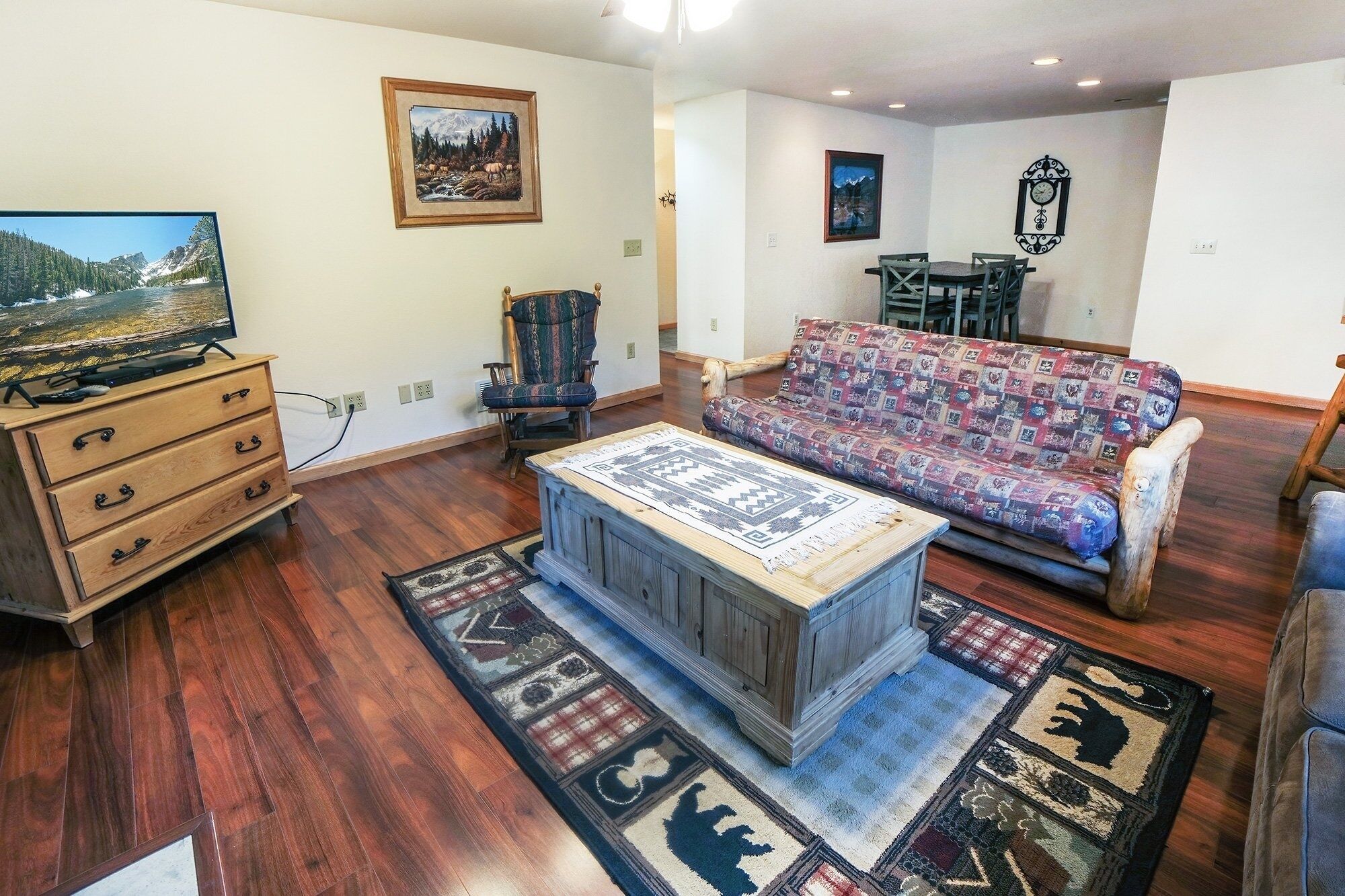 A living room with a wooden TV stand, a patterned sofa, a wooden coffee table, and a rug with animal prints.