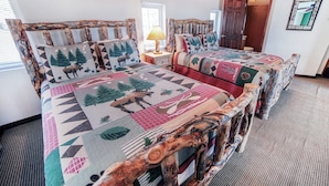 A room with a rustic wooden bed frame, a patterned bedspread, and a woven rug. - Lazy R Cottages: 16a 2 Bedroom Cabin (Estes Park)