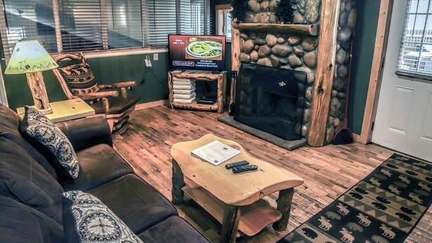 Una sala de estar acogedora con una chimenea de piedra, un televisor y un sofá cómodo.