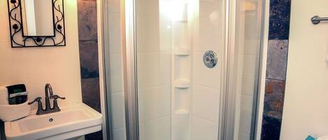 A bathroom with a glass-enclosed shower, a sink with a mirror, and a towel rack.