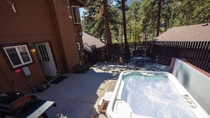 Un patio trasero con jacuzzi, muebles de jardín y una parrilla.