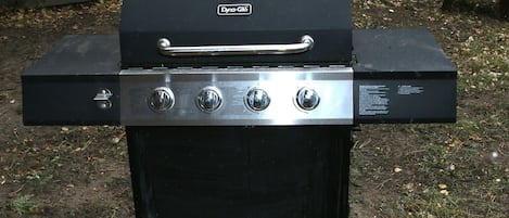 Un barbecue d’extérieur noir, doté d’une poignée et de quatre boutons de réglage.