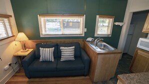 A compact kitchenette with a built-in sink, a small countertop, and a wooden bench. - Triple R Cottages: 2 1 Bedroom Cabin (Estes Park)
