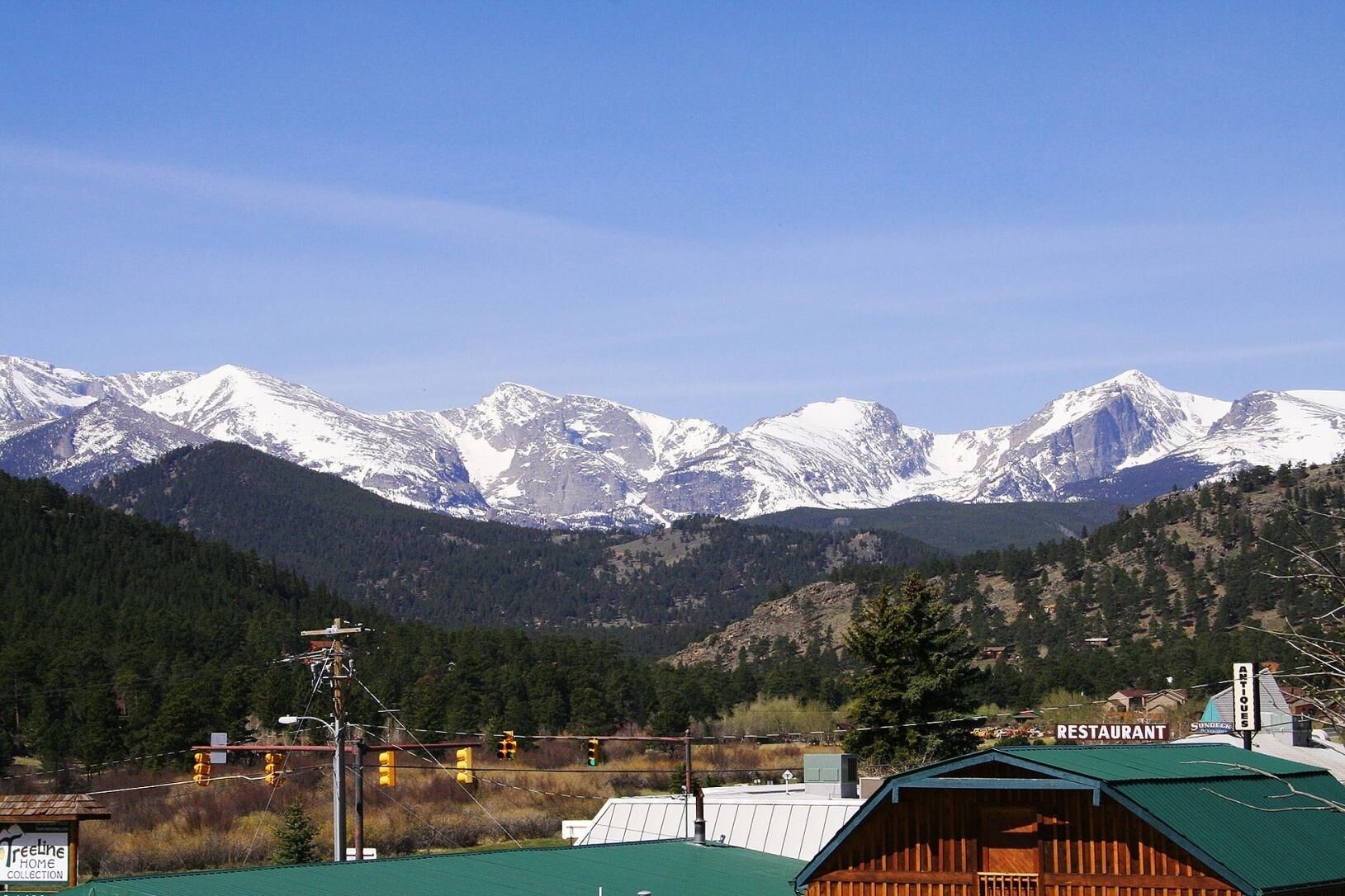 Un paysage de montagne avec des sommets enneigés, un restaurant et un bâtiment surmonté d’un toit végétalisé.