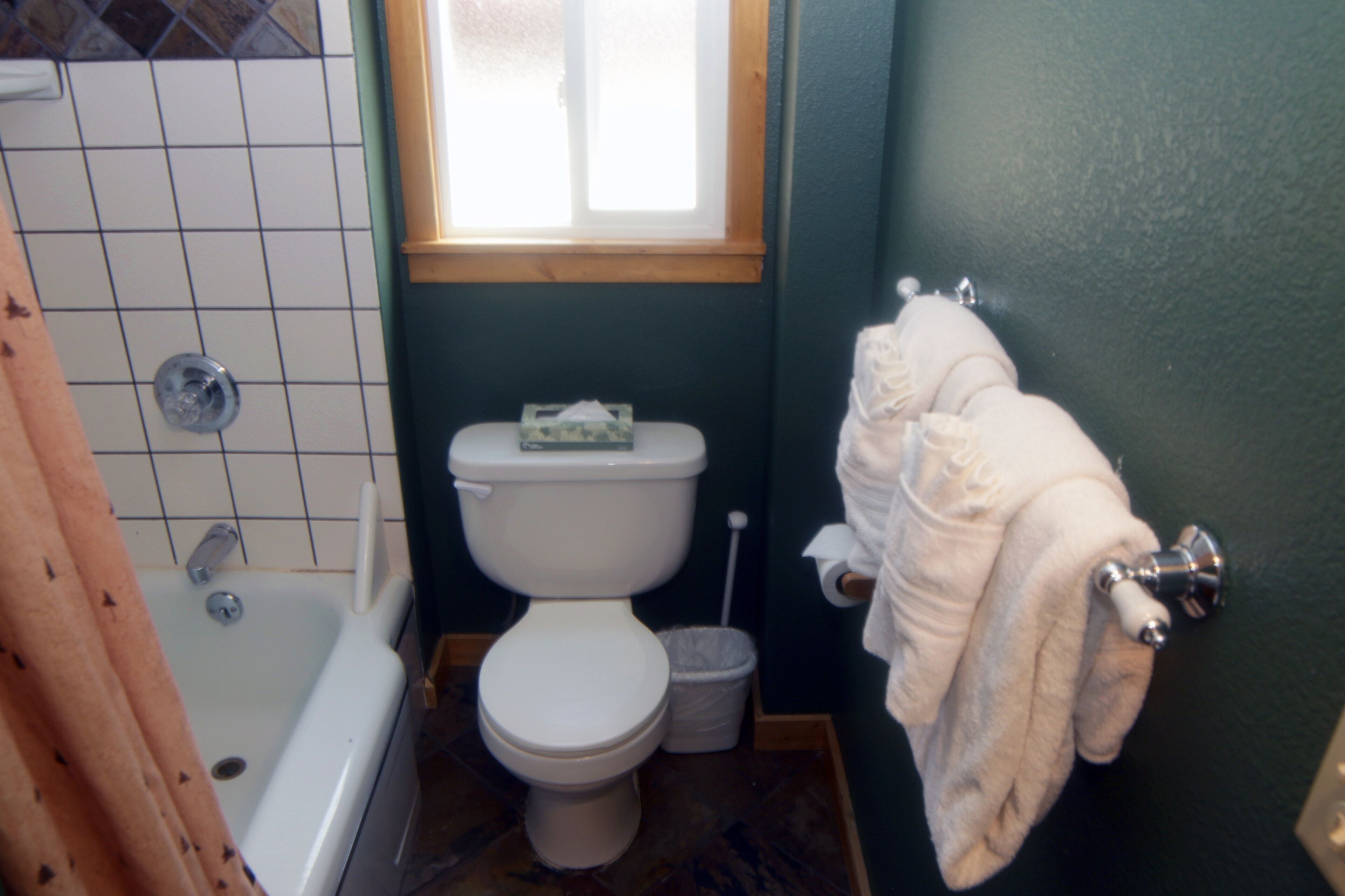 A bathroom with a bathtub, toilet, and a window.