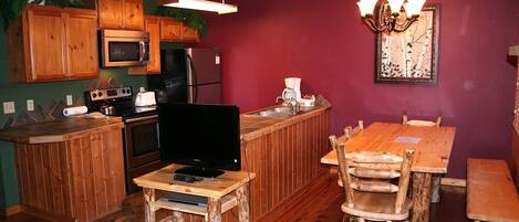 A compact kitchen with wooden cabinets, a microwave, a stove, and a sink.