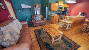 A cozy living room with a brown leather sofa, a wooden coffee table, and a patterned rug. - Lazy R Cottages: 17 2 Bedroom Cabin (Estes Park)