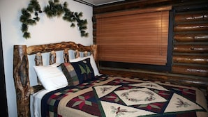 A bed with a wooden headboard, a quilt, and a wall-mounted garland. - Triple R Cottages: 1 3 Bedroom Cabin (Estes Park)