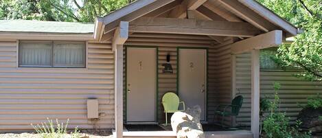 A small cabin with a porch, two doors, and a green chair outside.