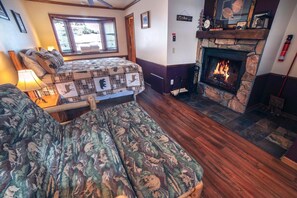 A cozy room with a fireplace, a bed with a quilt, and a chair with a floral pattern. - Sunnyside Knoll: 1 1 Bedroom Studio (Estes Park)