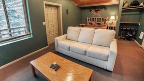 Un salon avec un canapé beige, une table basse en bois et une cheminée.