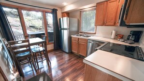 A modern kitchen with wooden cabinets, a stainless steel refrigerator, a dishwasher, and a gas stove. - Sunnyside Knoll: 7 1 Bedroom Cabin (Estes Park)