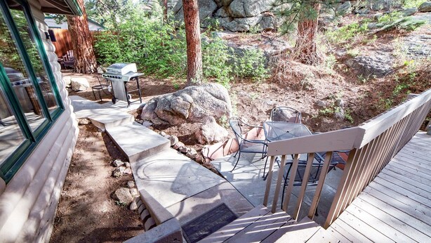 A wooden deck with outdoor seating, a barbecue grill, and a welcome mat. - Sunnyside Knoll: 7 1 Bedroom Cabin (Estes Park)