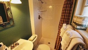 A bathroom with a sink, toilet, shower, and a mirror with decorative elements. - Triple R Cottages: 4 1 Bedroom Cabin (Estes Park)