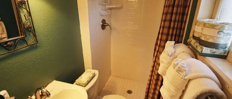 Un baño con lavamanos, inodoro, ducha y espejo con detalles decorativos.