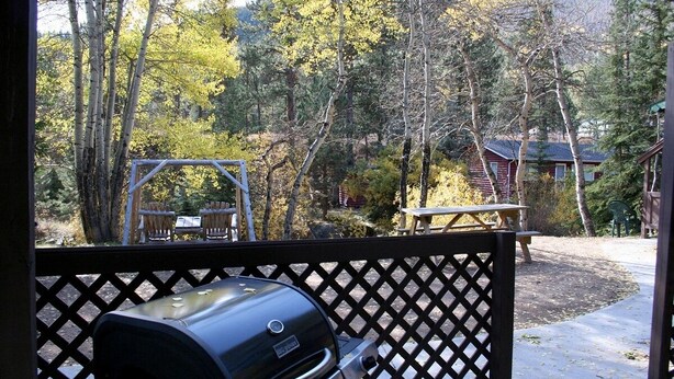 A backyard with a grill, picnic table, and wooden deck. - Fawn Valley Inn: 253 1 Bedroom Apts (Estes Park)